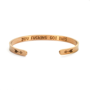 Macro shot of gold cuff bangle featuring internal YOU FUCKING GOT THIS engraving and arrow detail