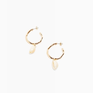 Detail of golden hammered hoop earrings with natural sea shells in bohemian style