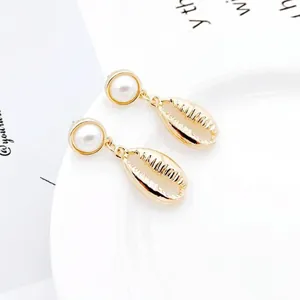 Detail of shell earrings featuring gold-plated metal and a central lustrous pearl