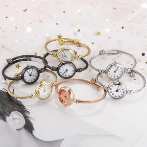 Flat lay of diverse quartz cuff watches in gold and silver on starry white gauze background