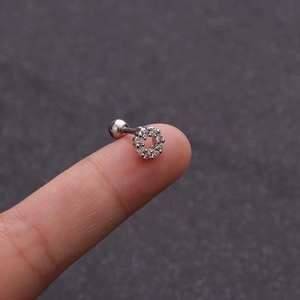 Macro shot of a small stainless steel hollow circle stud earring with zircon on a fingertip