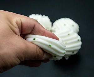 Squeezing a soft white PU foam bun squishy toy with green sequins for stress relief