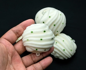 Close-up of white spiral textured holiday ball with green glitter dots held in hand