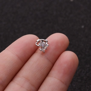 Macro shot of a silver cubic zirconia small hoop earring held between fingers