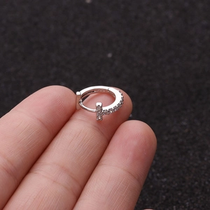 Macro shot of silver hinged hoop earring with zircon stones and a T-shaped design