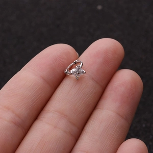 Detailed macro view of a tiny silver clover earring with four clear cubic zirconia stones