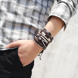 Detail of layered leather bracelet set with woven leaf charms on a male wrist