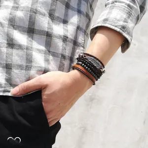Men's layered leather bracelet featuring leaf metal charm and woven wood beads on wrist