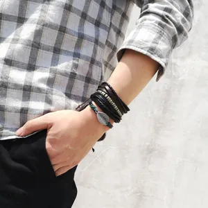 Detail of multi-layer men's leather bracelet set with silver leaf pendant and woven cords