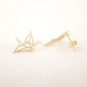 Vista macro dettagliata di orecchini a gru in origami dorati con finitura opaca
