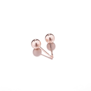 Macro shot of rose gold ball earrings featuring a high-polish mirror finish surface