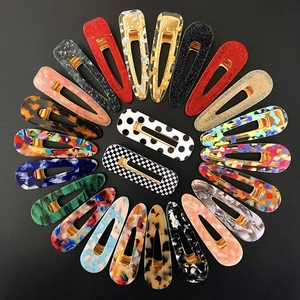 Assorted acetate hair clips in colorful marble and patterns arranged on black background
