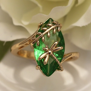 Macro detail of dragonfly and olive green gemstone on a golden branch ring band