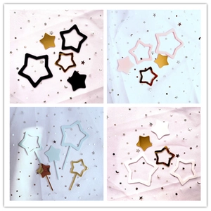 Close-up of star-shaped laser acrylic cake toppers in various colors on tulle fabric