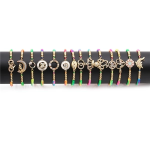 Set of 12 colorful braided bracelets with gold plated cubic zirconia cross pendants