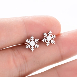 Minimalist silver snowflake stud earrings in vintage style shown on fingers for size