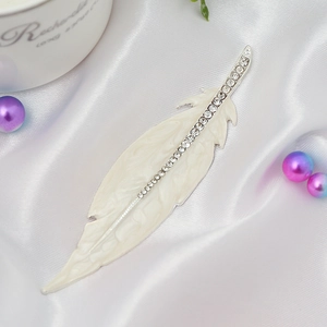 Close-up of cream feather jewelry with inlaid rhinestones on a white silk background