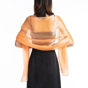 Detail of sheer orange chiffon shawl with light texture draped over an evening dress