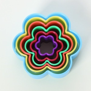 Top-down view of 6 colorful nesting flower-shaped plastic cookie cutters for baking