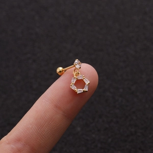 Macro shot of a tiny gold stainless steel cartilage earring with hexagonal zircon pendant