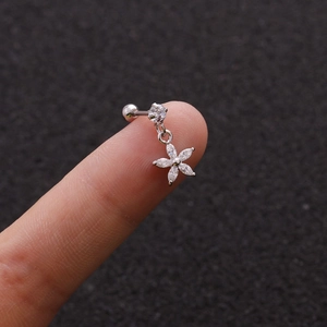 Macro detail of silver flower cartilage stud with cubic zirconia on a gray surface