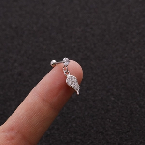 Macro view of a silver wing pendant earring with clear crystals on a fingertip