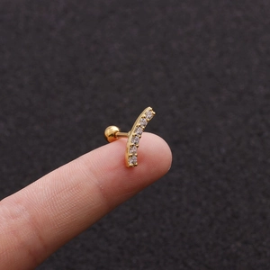 Macro shot of 18K gold curved cartilage stud earring with cubic zirconia on fingertips