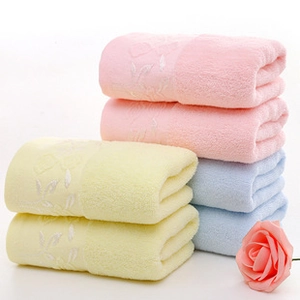 Detail of stacked cotton towels featuring exquisite white floral embroidery and soft textures