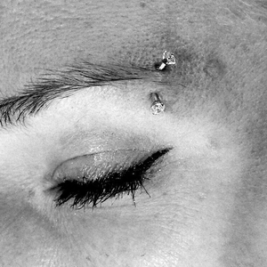 Close-up of curved eyebrow piercing with sparkling round cubic zirconia stones in stainless steel