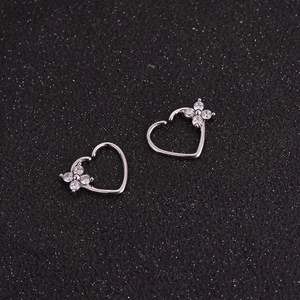 Detail of silver heart-shaped earrings with micro-inlaid clover on black texture