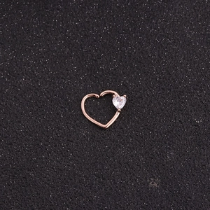 Macro shot of rose gold heart-shaped piercing ring with a sparkling clear zircon stone
