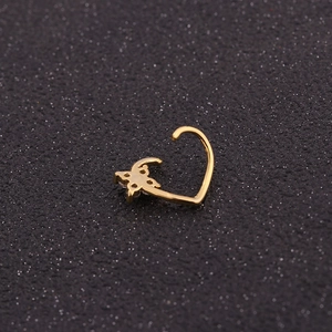 Close-up of golden clover ear piercing with micro-pave zircons on a dark background