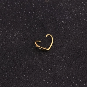 Close-up of heart-shaped gold nose ring with micro-pave cubic zirconia on black surface