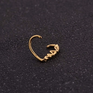 Detailed macro view of a golden scorpion-shaped nose ring with intricate metallic textures