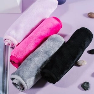 Macro shot of rolled microfiber towels in pink, rose, gray and black on purple surface