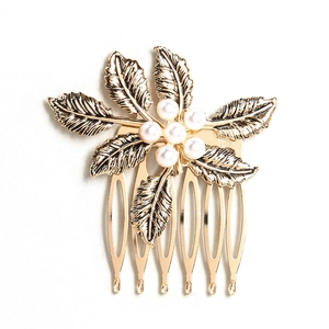 Vintage gold leaf hair comb with elegant white pearls on a minimalist white background