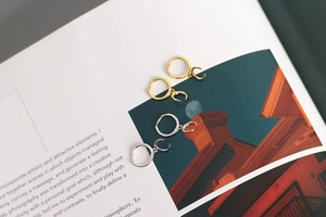Detail of silver and gold crescent moon hoop earrings displayed on an artistic magazine