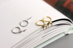 Detail of silver and gold crescent moon dangle earrings on a book page surface