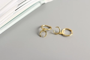 Detail of gold-plated S925 sterling silver crescent moon pendant hoop earrings on grey base