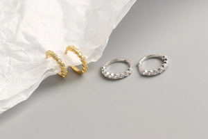 Macro shot of gold and silver S925 sterling silver hoop earrings with diamond pavé accents