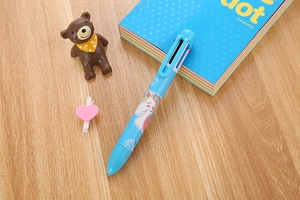 Detail of light blue unicorn multi-color ballpoint pen on a cute desktop setting