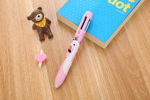 Detail of pink multi-color flamingo ballpoint pen on a wooden desk with stationery
