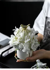 Detailed view of artificial flowers inside a golden wire birdcage with ceramic base