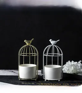 Close-up of golden birdcage metal frame with white ceramic pot and bird ornament