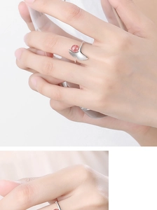 Detailansicht eines silbernen Fischschwanz-Rings mit rosa Erdbeerkristall am Finger