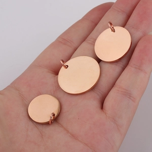 Three rose gold round pendant charms in various sizes shown in a hand for scale