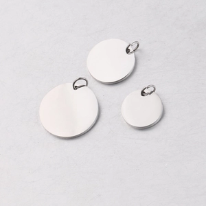 Detailed view of three polished stainless steel round pendants with rings in various sizes
