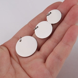 Polished stainless steel blank round pendant charms in three sizes held in palm