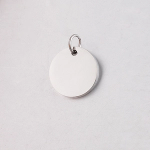 Macro shot of silver mirror-polished stainless steel round pendant with connecting loop