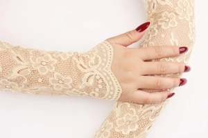 Close-up of beige floral lace arm sleeves showing intricate hollow-out texture